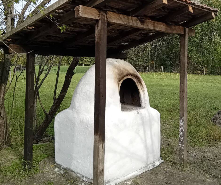 Fehérre meszelt kemence, zöld mezőn.